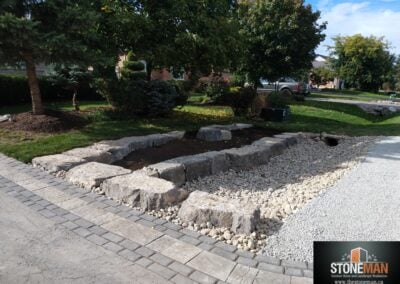 Driveway banding with armour stone retaining wall and river rock